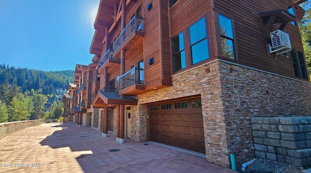 view of side of property featuring a balcony, stone siding, and an attached garage