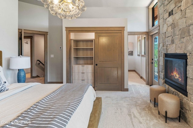 bedroom with baseboards, a fireplace, a chandelier, and light colored carpet