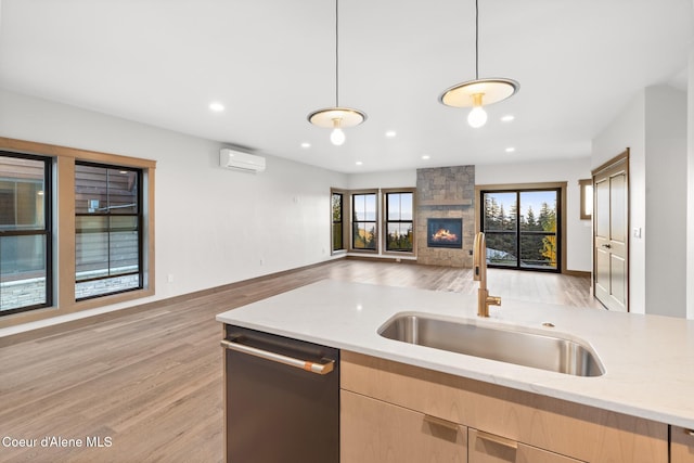 kitchen featuring a wall mounted air conditioner, light brown cabinetry, dishwasher, a sink, and open floor plan