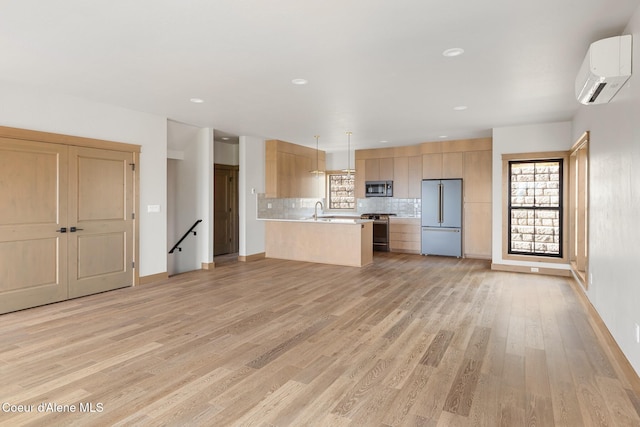 kitchen featuring a peninsula, stainless steel appliances, light countertops, decorative backsplash, and a wall mounted AC