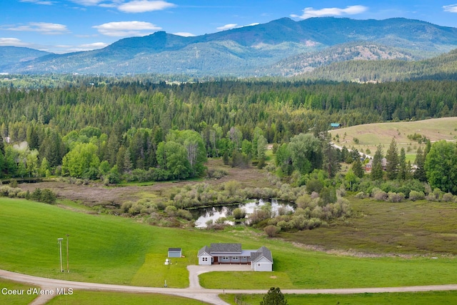 aerial view of property and surrounding area featuring mountains and a heavily wooded area