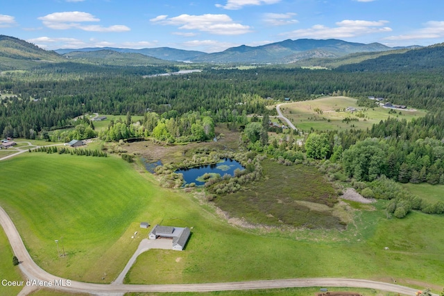 view of property location with a forest and a water and mountain view