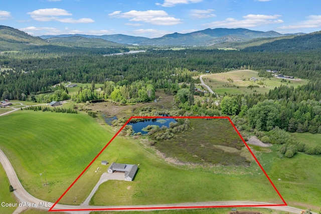 aerial view of property's location featuring a forest, a mountain backdrop, and property parcel outlined