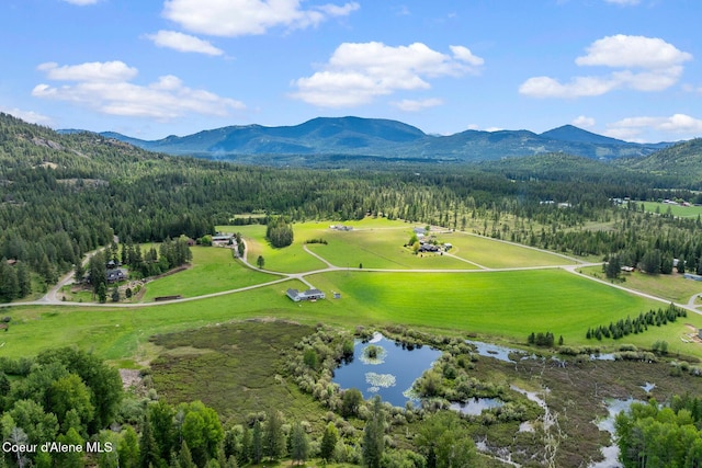drone / aerial view of a heavily wooded area and a water and mountain view