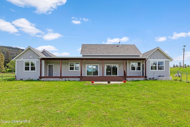 back of property featuring board and batten siding, a lawn, and crawl space