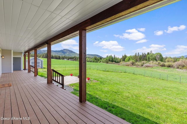 wooden deck featuring a mountain view, a view of rural / pastoral area, a storage unit, and an outbuilding