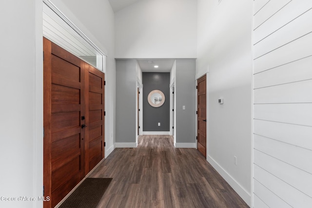 foyer featuring dark wood-style flooring, baseboards, and a towering ceiling