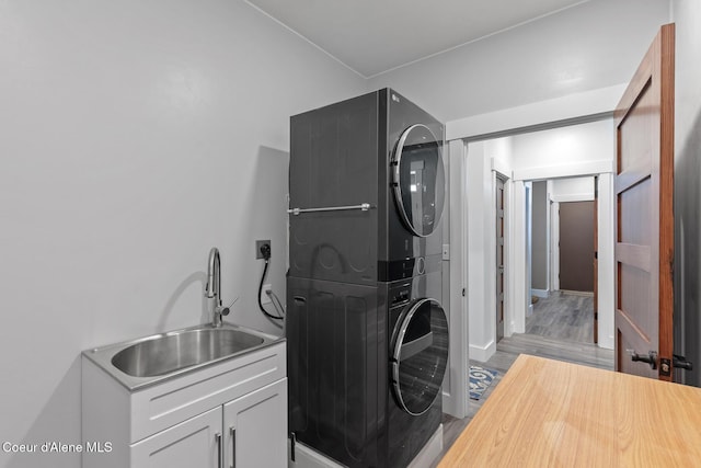 laundry area with stacked washer / dryer and baseboards