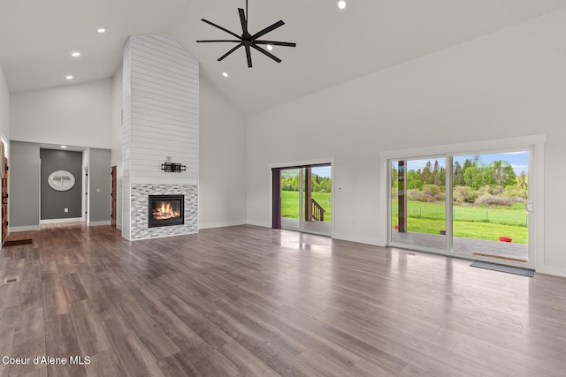 unfurnished living room with high vaulted ceiling, a ceiling fan, a fireplace, baseboards, and wood finished floors