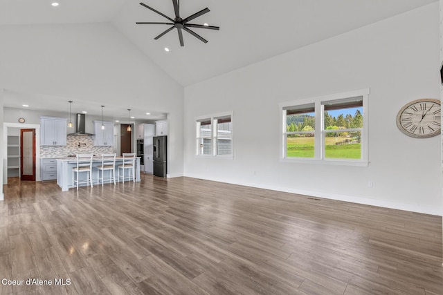 unfurnished living room with high vaulted ceiling, dark wood-type flooring, ceiling fan, and recessed lighting