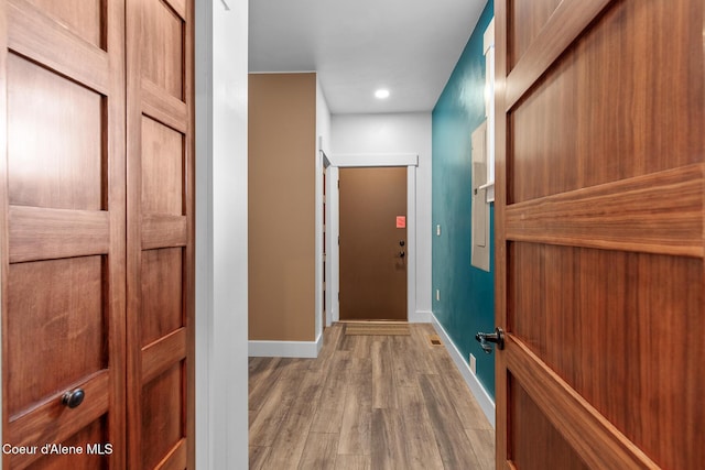corridor with wood finished floors, baseboards, and recessed lighting