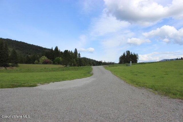 view of asphalt road with a view of rural / pastoral area and a wooded view