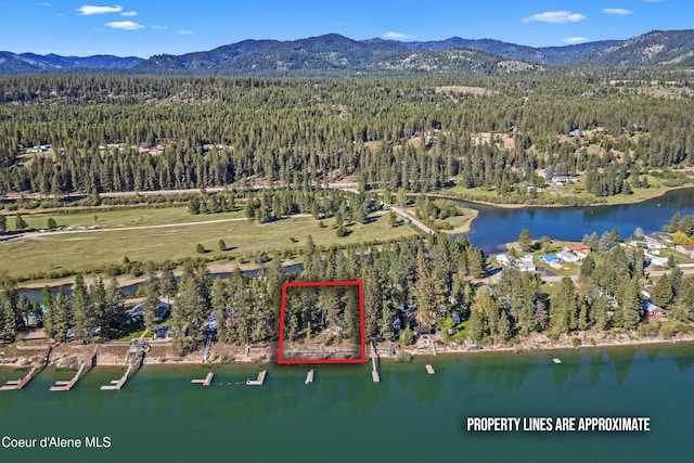 aerial view of property's location featuring a heavily wooded area, property boundaries highlighted, and a water and mountain view