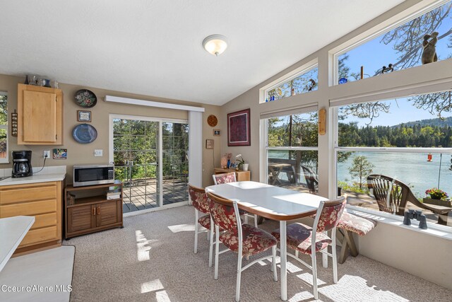 dining area featuring light colored carpet and lofted ceiling