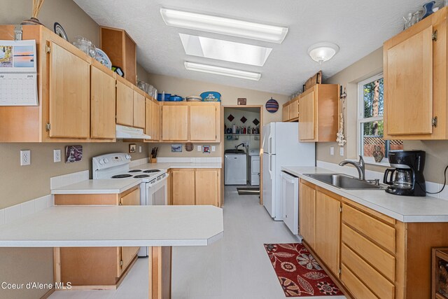 kitchen with under cabinet range hood, white appliances, separate washer and dryer, a sink, and light countertops