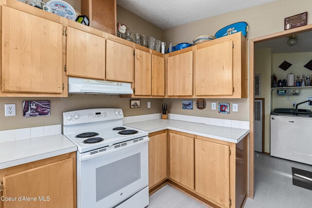 kitchen featuring white electric range, under cabinet range hood, washer / dryer, light countertops, and light brown cabinets