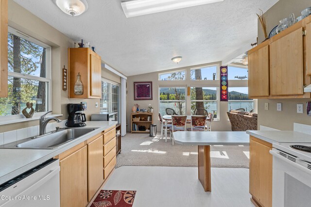 kitchen featuring white appliances, a sink, vaulted ceiling, light countertops, and a textured ceiling
