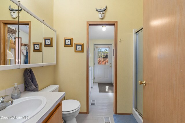 bathroom featuring a shower stall, vanity, toilet, and baseboards
