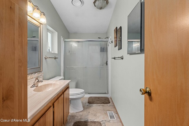 full bathroom featuring a shower stall, vanity, toilet, stone finish flooring, and baseboards