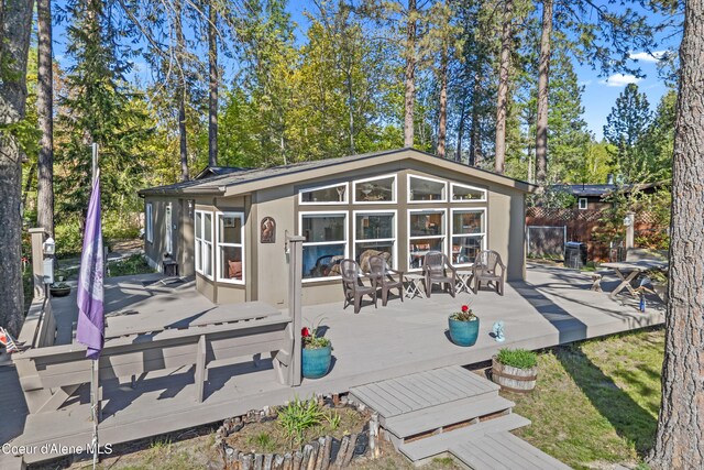 back of property with a wooden deck, an outdoor structure, stucco siding, and fence