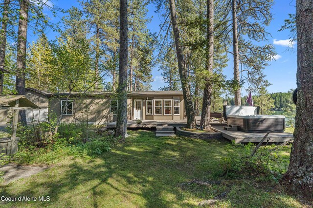 rear view of property featuring a wooden deck, a lawn, and a sunroom