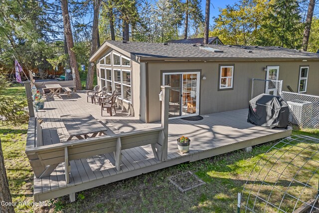 rear view of property featuring a shingled roof and a deck