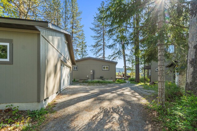 view of side of home featuring a garage and gravel driveway