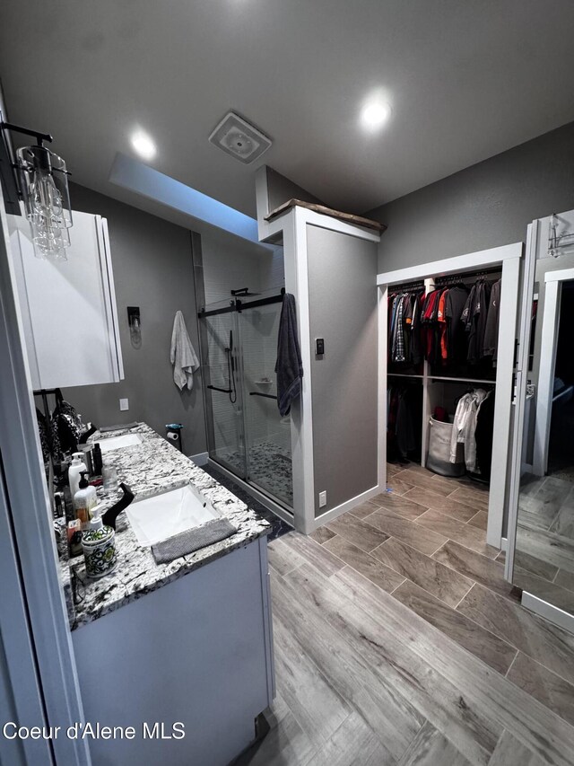 10320 N Payment Peak Rd, Hauser, ID 83854 - bathroom featuring a walk in closet, double vanity, a shower stall, and a sink