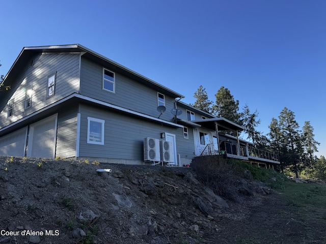 10320 N Payment Peak Rd, Hauser, ID 83854 - back of property with an attached garage, a wooden deck, and ac unit