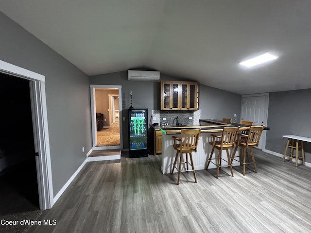 10320 N Payment Peak Rd, Hauser, ID 83854 - kitchen featuring a wall unit AC, dark wood-style floors, lofted ceiling, glass insert cabinets, and brown cabinets