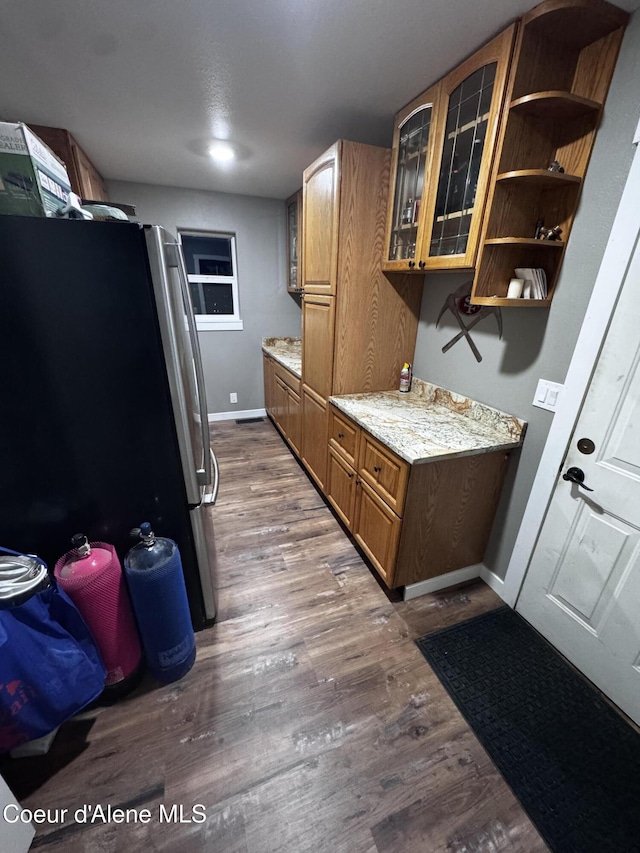 10320 N Payment Peak Rd, Hauser, ID 83854 - kitchen with freestanding refrigerator, wood finished floors, glass insert cabinets, brown cabinets, and baseboards
