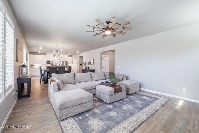 7102 S Hever St, Cheney, WA 99004 - living room with light wood-type flooring, baseboards, a chandelier, and ceiling fan