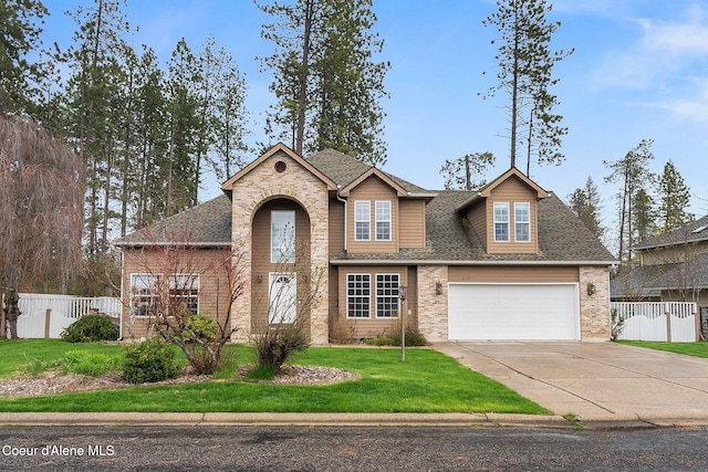 traditional-style house with fence, a garage, a shingled roof, concrete driveway, and a front lawn