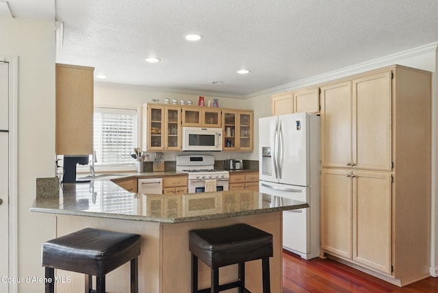 2123 Browning Way, Sandpoint, ID 83864 - kitchen with a peninsula, light brown cabinetry, a breakfast bar, a sink, and white appliances