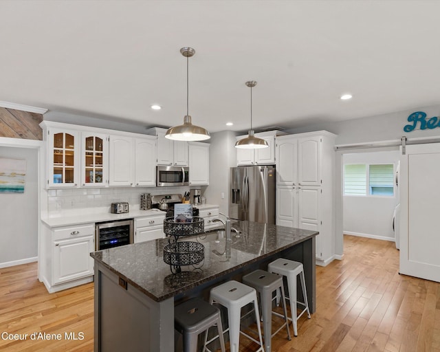 kitchen with stainless steel appliances, white cabinets, a kitchen breakfast bar, and recessed lighting