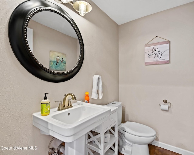 half bathroom with toilet, baseboards, and wood finished floors