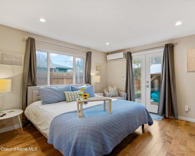 bedroom with a wall unit AC, multiple windows, access to outside, light wood-style flooring, and recessed lighting