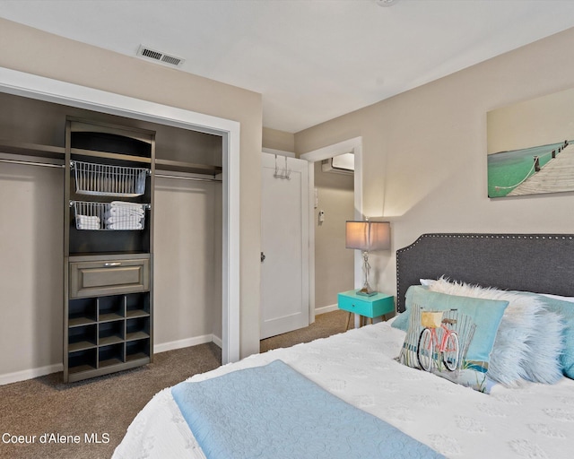 carpeted bedroom featuring baseboards, a wall mounted AC, and a closet
