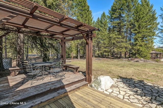 762 Reeder Bay Rd, Nordman, ID 83848 - wooden terrace featuring a pergola, a yard, outdoor dining area, and view of scattered trees