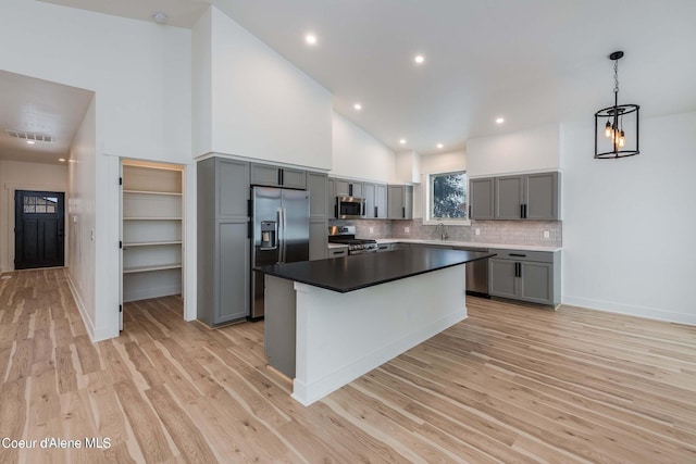 215 White Cloud Dr, Sandpoint, ID 83864 - kitchen featuring gray cabinetry, appliances with stainless steel finishes, light wood-type flooring, backsplash, and high vaulted ceiling