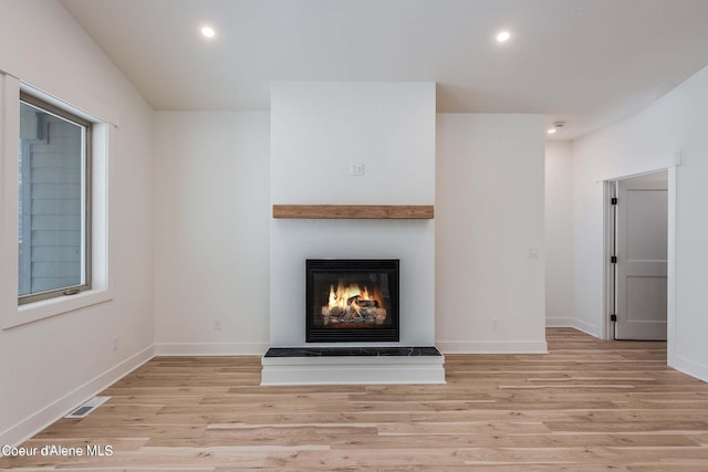 215 White Cloud Dr, Sandpoint, ID 83864 - unfurnished living room featuring wood finished floors, a glass covered fireplace, recessed lighting, and baseboards