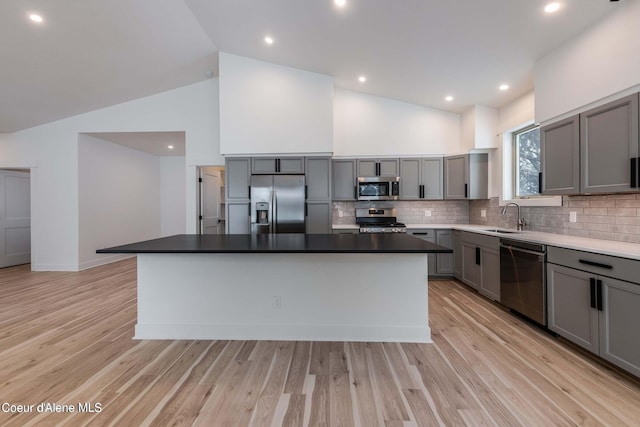 215 White Cloud Dr, Sandpoint, ID 83864 - kitchen with appliances with stainless steel finishes, gray cabinets, decorative backsplash, a kitchen island, and a sink