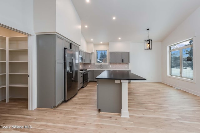 215 White Cloud Dr, Sandpoint, ID 83864 - kitchen featuring gray cabinetry, appliances with stainless steel finishes, backsplash, light wood finished floors, and high vaulted ceiling