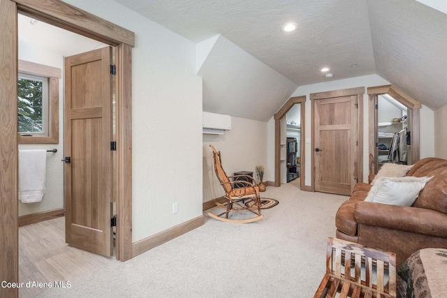 215 White Cloud Dr, Sandpoint, ID 83864 - living area with lofted ceiling, baseboards, a wall unit AC, light colored carpet, and a textured ceiling