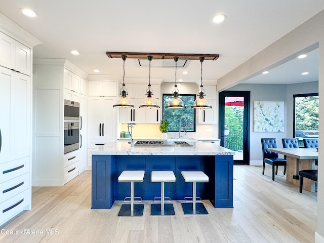 15818 N Morgan Ln, Hayden, ID 83835 - kitchen featuring light wood-type flooring, white cabinetry, light stone counters, recessed lighting, and a large island with sink