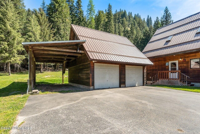garage with a detached garage and a view of trees