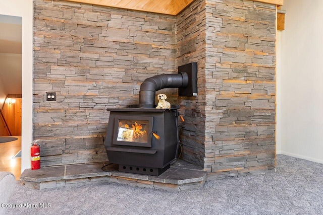 detailed view of carpet, a wood stove, baseboards, and a fire extinguisher