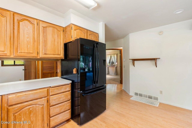kitchen featuring freestanding refrigerator, light wood-style flooring, light countertops, and baseboards