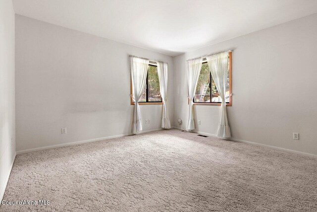 carpeted spare room featuring baseboards