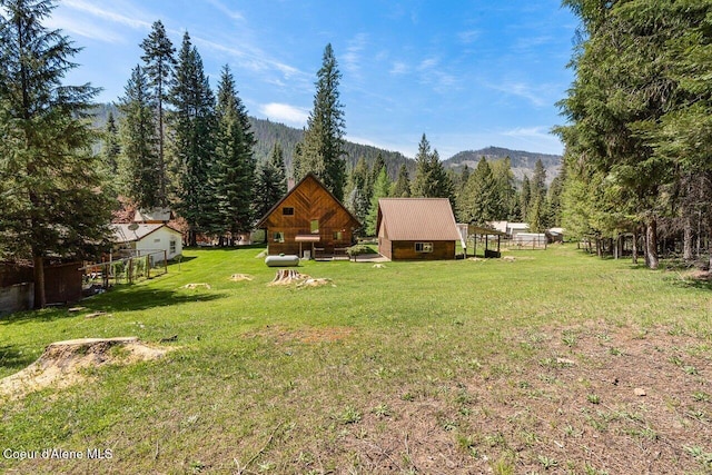 view of yard featuring a mountain view, a view of trees, and an outbuilding